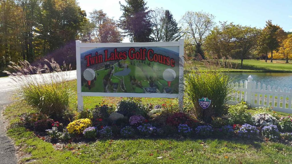 The Twin Lakes Golf Course entrance sign framed by autumn flowers